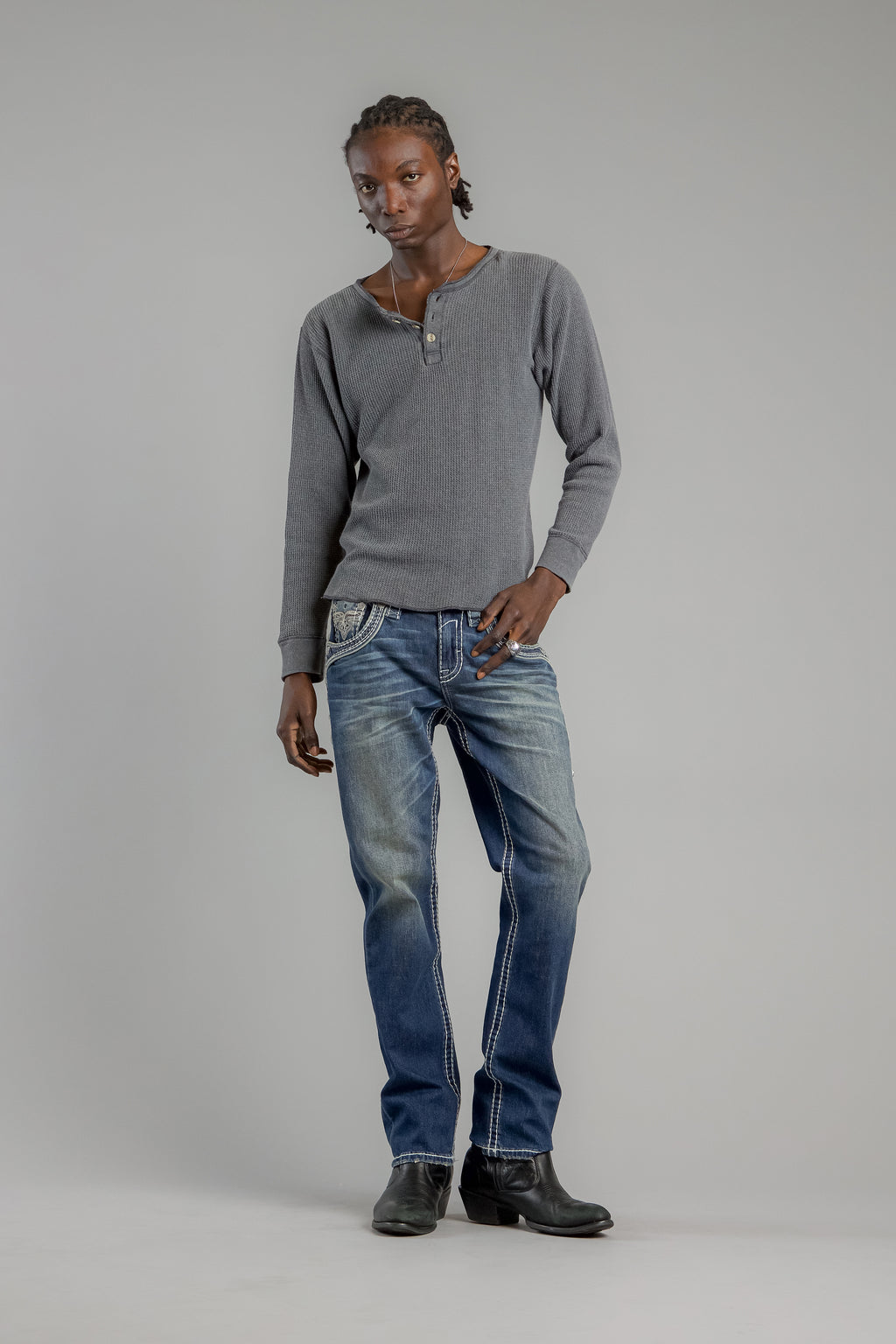 Person wearing a gray sweater and blue jeans on a plain background