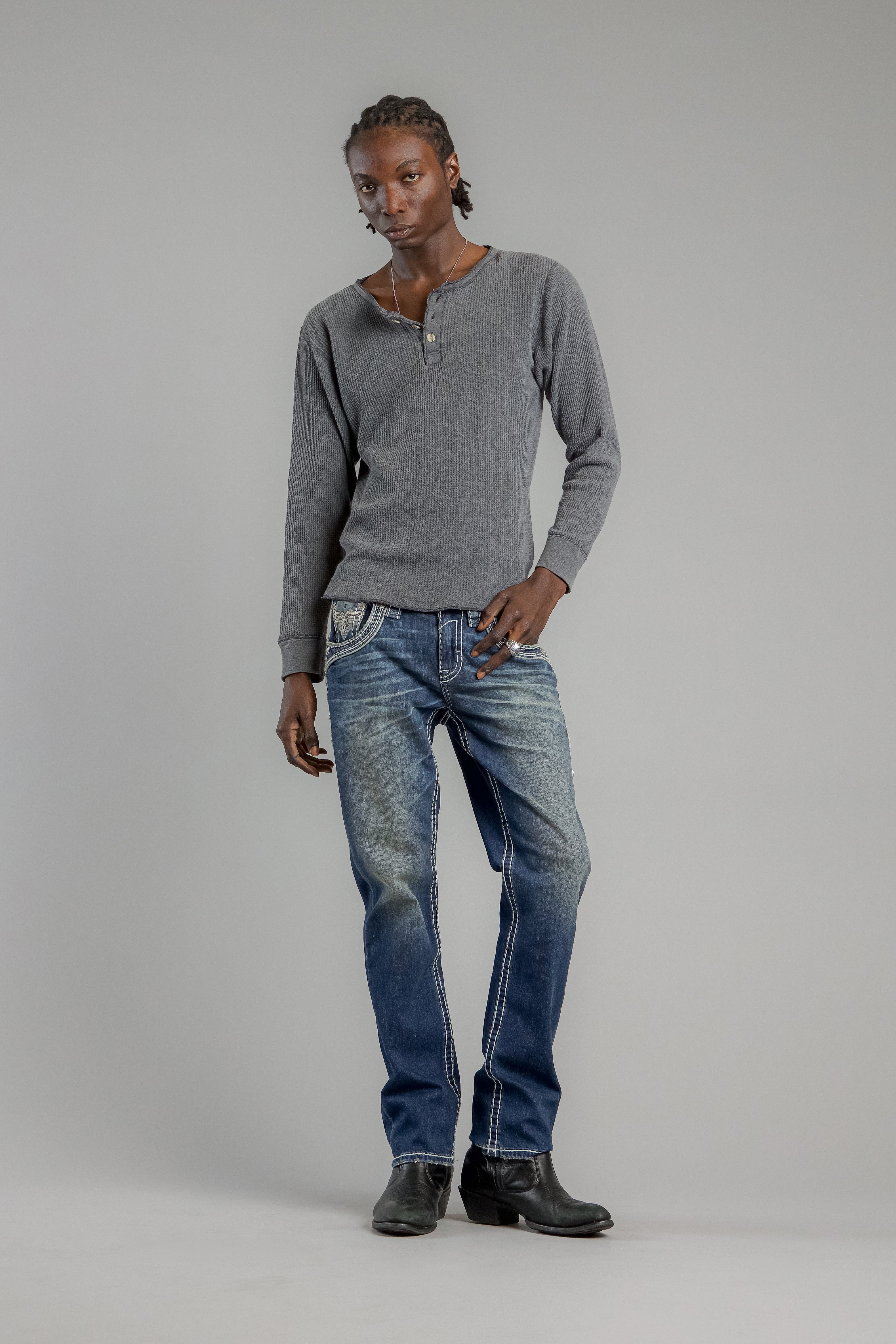 Person wearing a gray sweater and blue jeans on a plain background