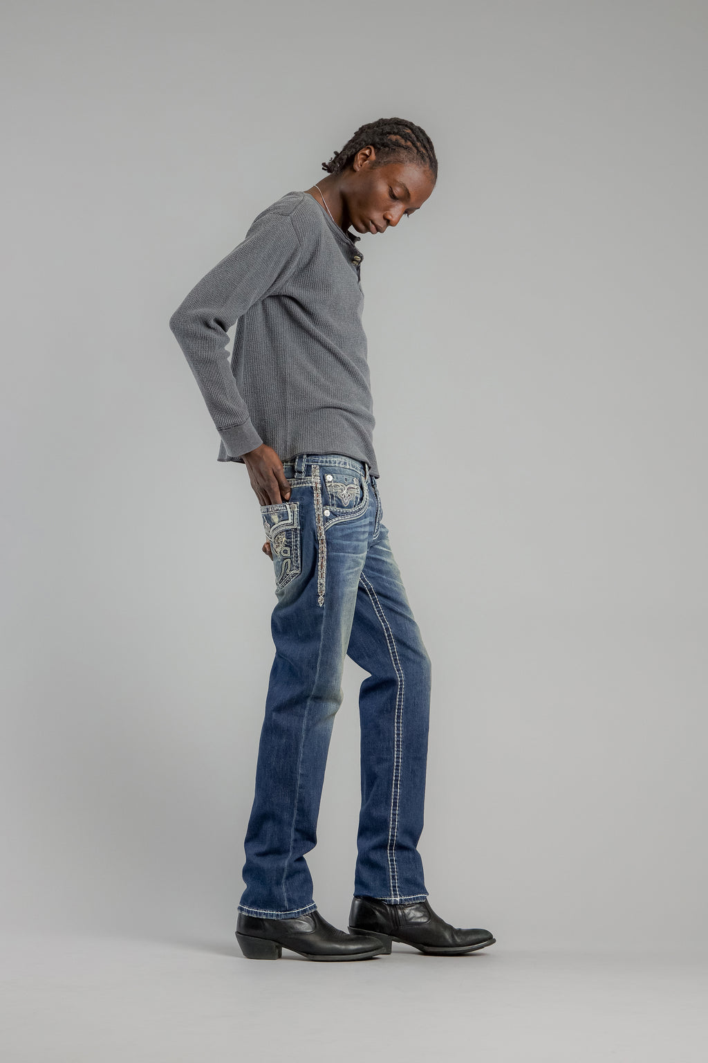 Person wearing a gray sweater and blue jeans on a plain background