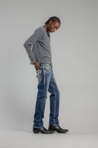 Person wearing a gray sweater and blue jeans on a plain background