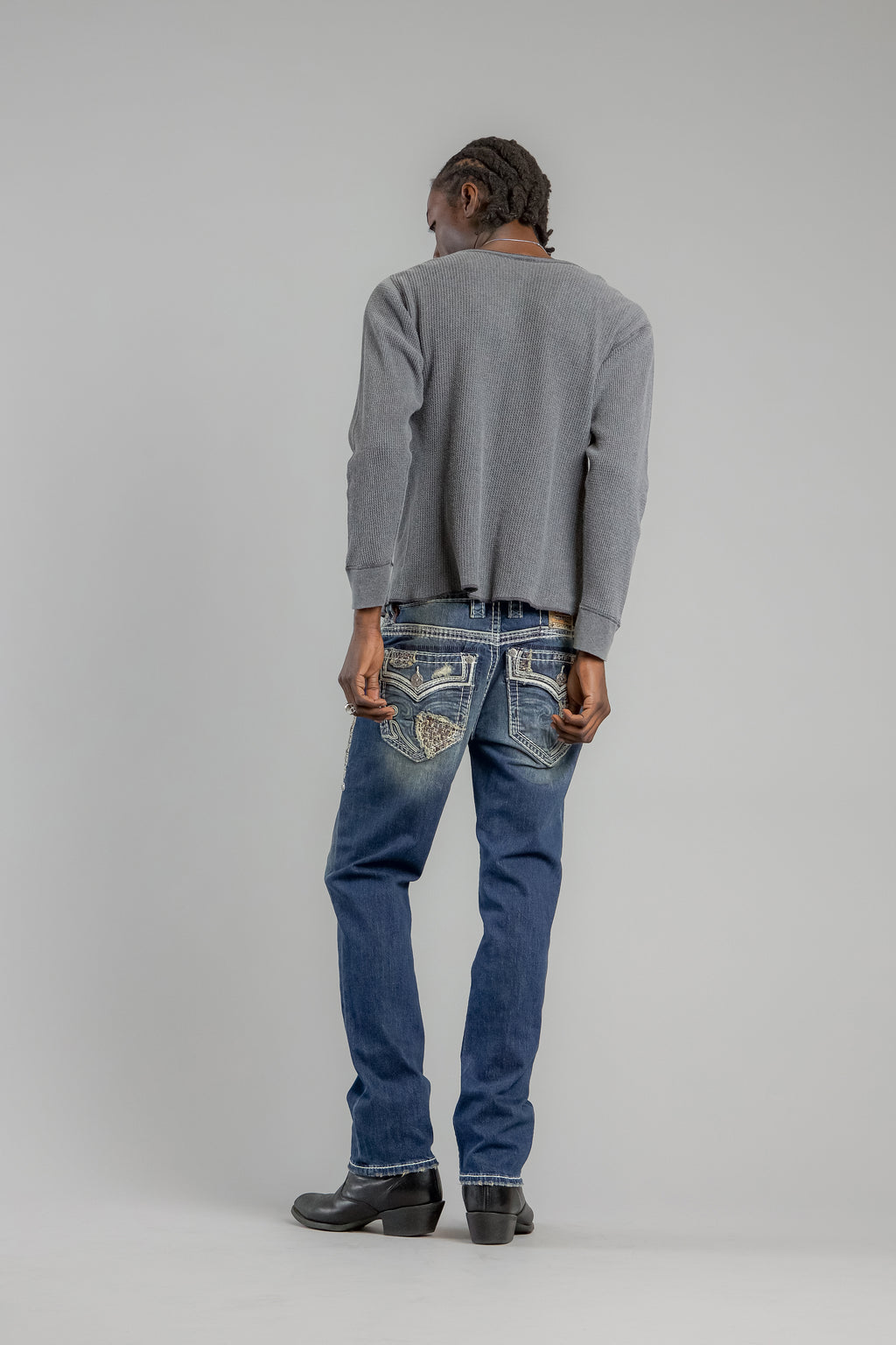 Person wearing a gray sweater and blue jeans on a plain background