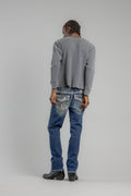 Person wearing a gray sweater and blue jeans on a plain background